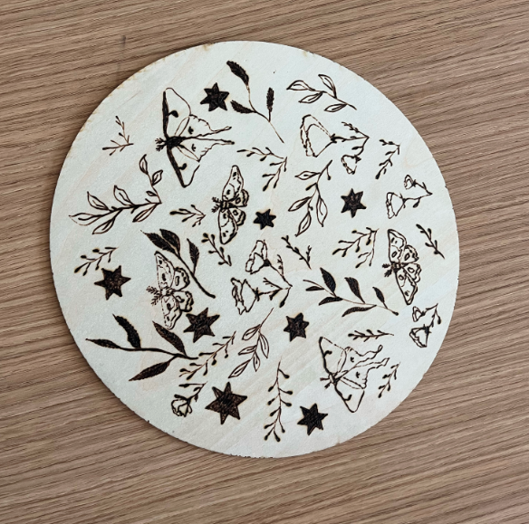 moths and leaves wood burned into circular piece of wood
